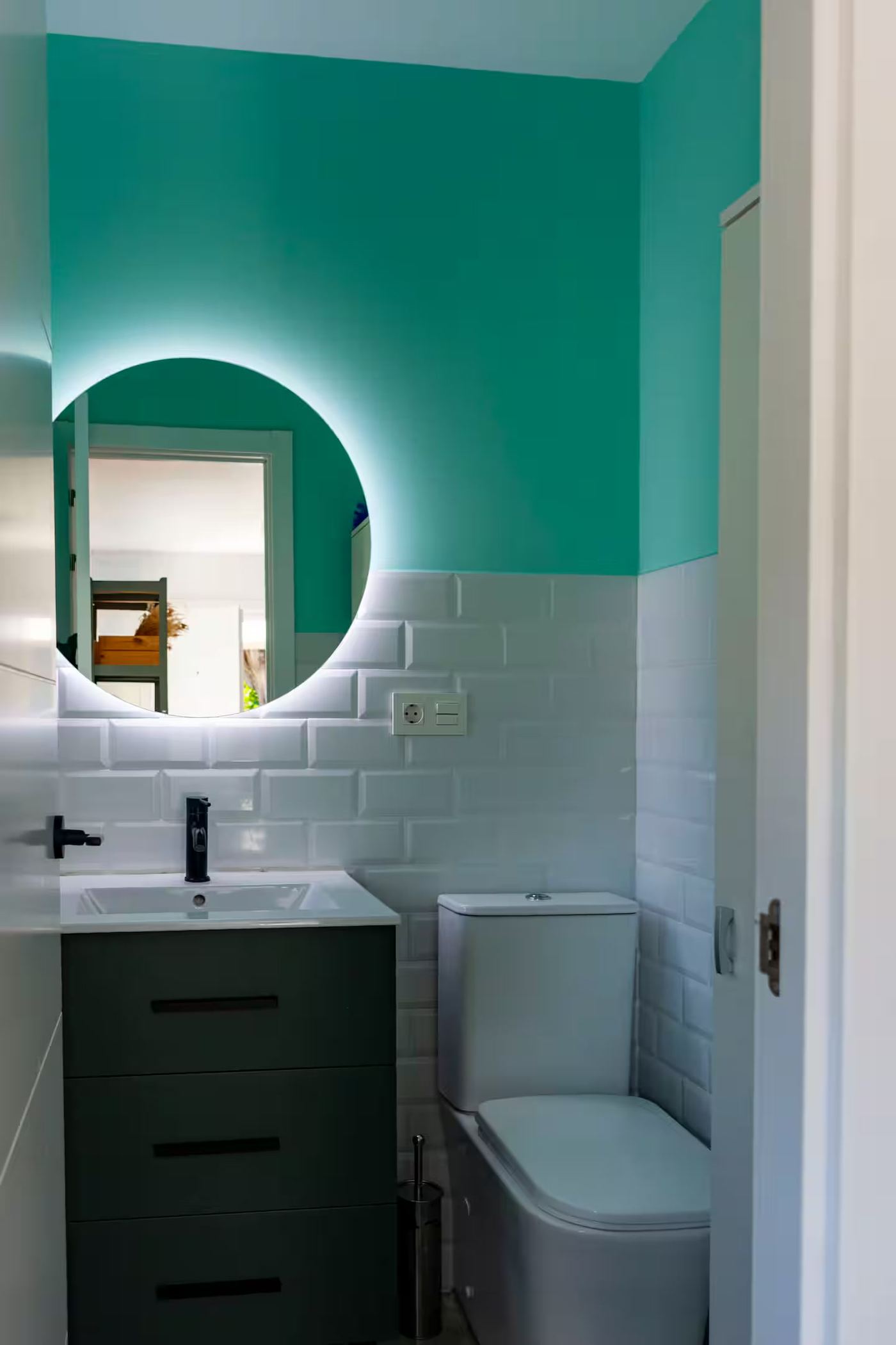 Baño con espejo redondo turquesa